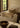 Sebuah ruang tamu sederhana yang dilengkapi dengan bantal bernada kebumian yang terbuat dari goni dan sutra. Ruangan ini ditata dengan sofa putih dan kayu antik yang kontras.