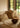 Ruang tamu bergaya pedesaan yang didekorasi dengan bantal yang ditenun tangan bernuansa sederhana dan lembut di atas sofa tiga dudukan berwarna putih.
